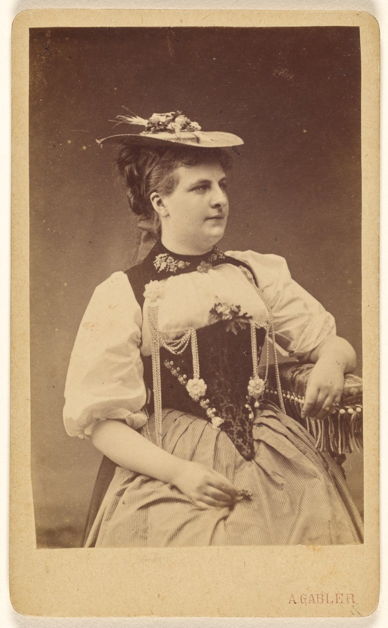 [Ongeïdentificeerde vrouw in klederdracht met hoed, zittend]. door A. Gabler