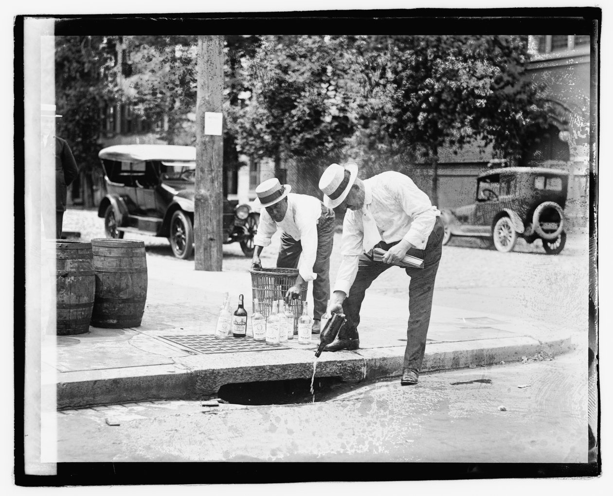 Twee mannen die drank in een riool gieten, 8 juli 1921 door American Photographer