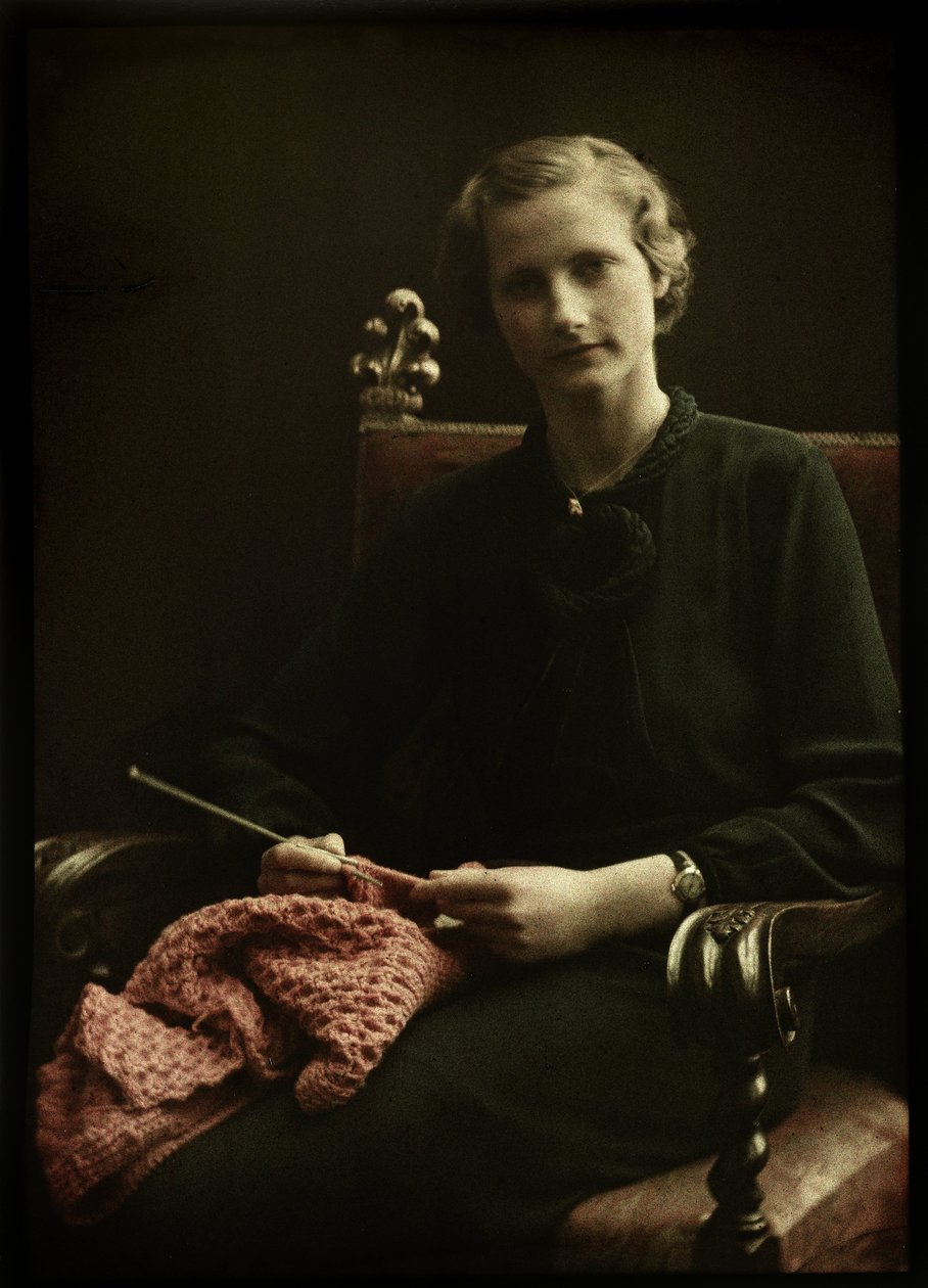 Portret van een vrouw, zittend in een stoel, met breiwerk in de hand door Anonymous