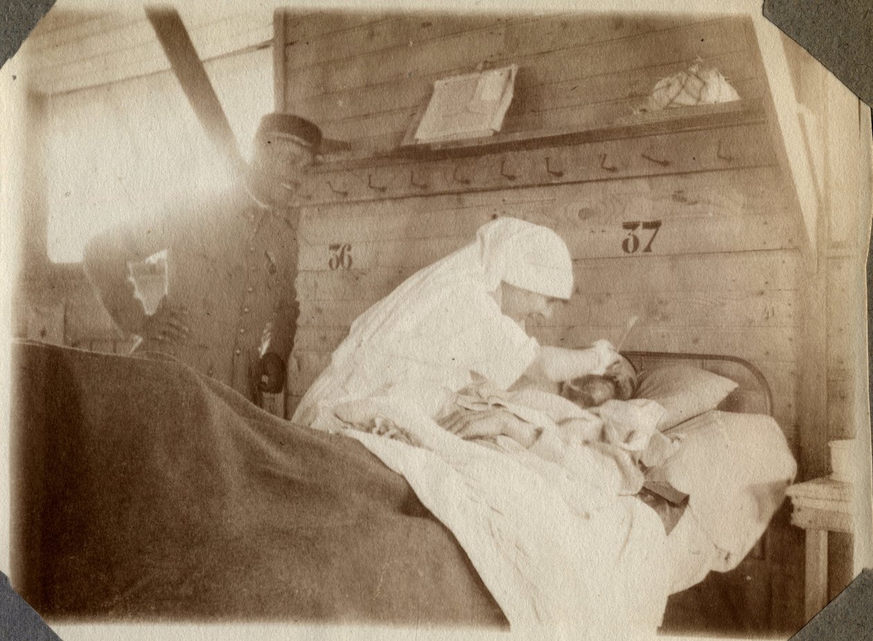 Eerste Wereldoorlog 1914-1918: verpleegster in een blouse scheert een soldaat (Franse oorlogswonden liggen in een bed), in Couville, Manche, Basse-Normandie, Frankrijk. Anonieme foto juli 1917. Privécollectie, Stella. door Anonymous Anonymous