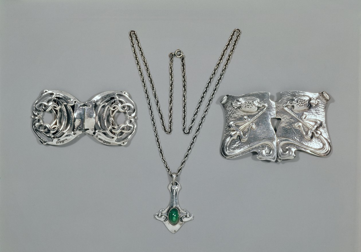 Zilveren sieraden ontworpen voor Liberty. Van links naar rechts: Taille gesp met verstrengeld Keltisch ontwerp, 1904. Hanger en ketting met cabochon geslepen chrysopraas. Taille gesp met repoussé ontwerp op gehamerd door Archibald Knox
