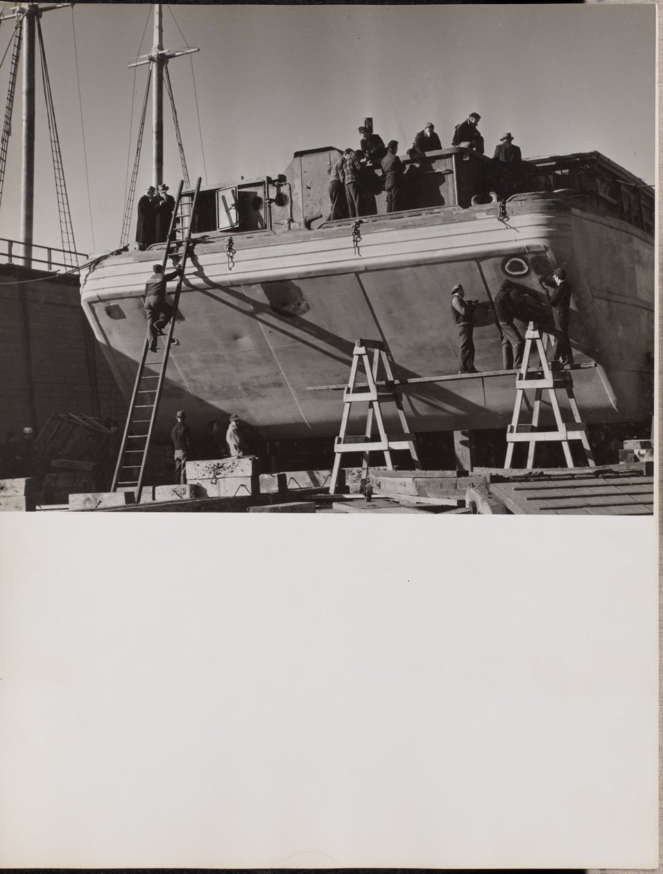[Een groep mannen werkt aan een aangemeerde boot]. door Arnold Eagle