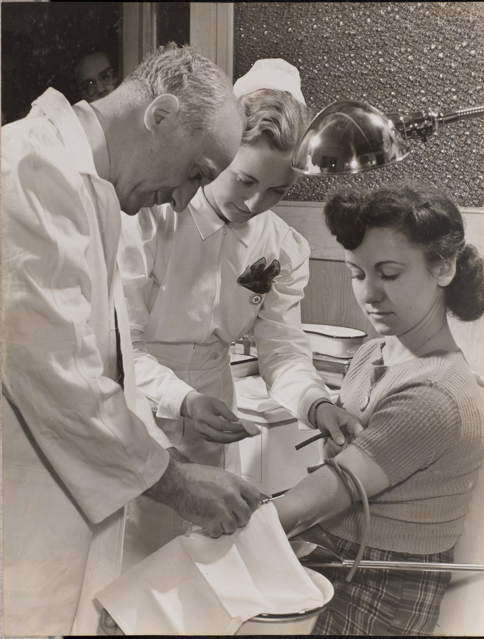 [Dokter en verpleegster steken een naald in de arm van een vrouw]. door Arnold Eagle