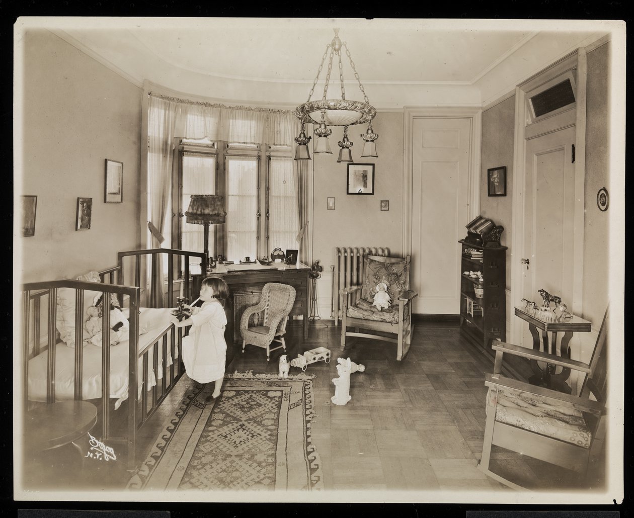 Een meisje dat een kaars vasthoudt, klimt in een wieg, in een slaapkamer van de A.C. Cronin residentie, 1915-16 door Byron Company