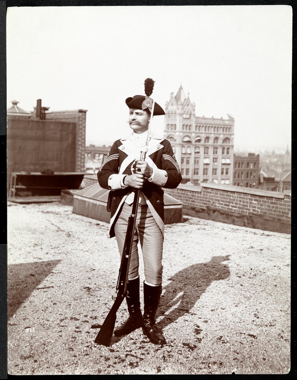 Een man op een dak gekleed in een traditioneel militair uniform, met een geweer, 1895 door Byron Company
