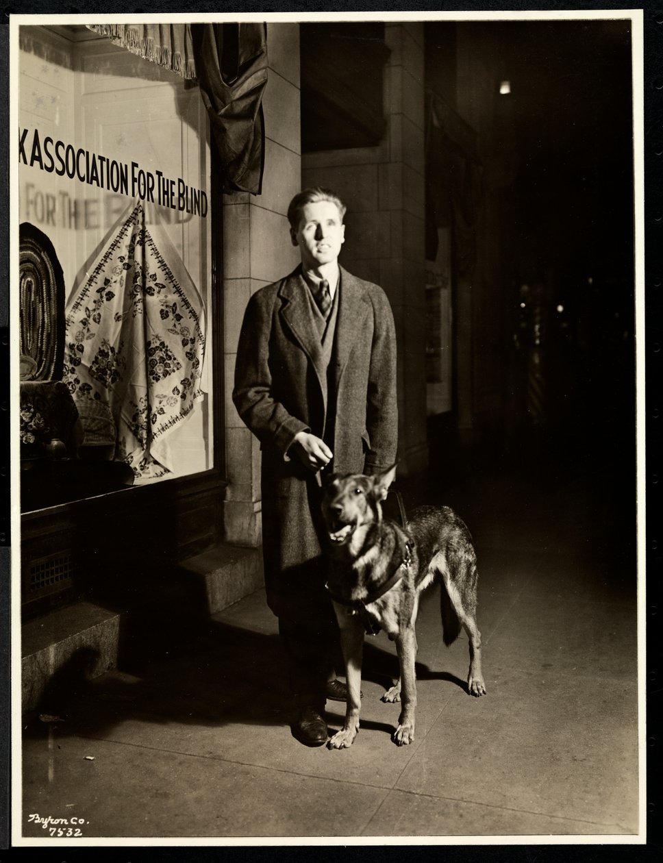 Blinde man en zijn geleidehond op de stoep voor de New York Association for the Blind, 111 East 59th Street, New York, 1938 door Byron Company