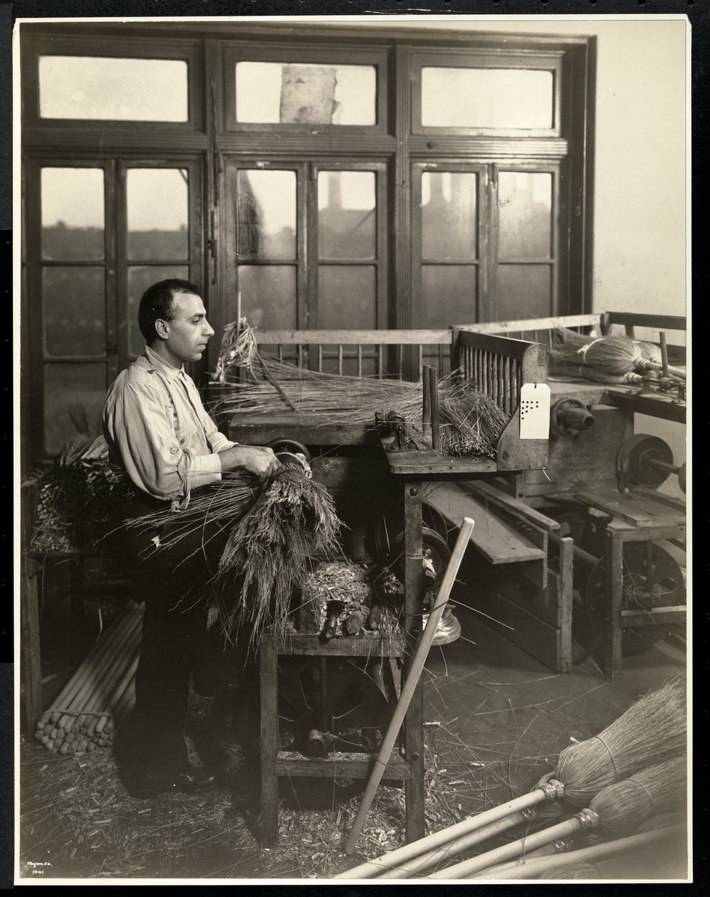 Blinde man die stro aan bezemstelen bevestigt in het Bourne Memorial Building, New York, 1921 door Byron Company