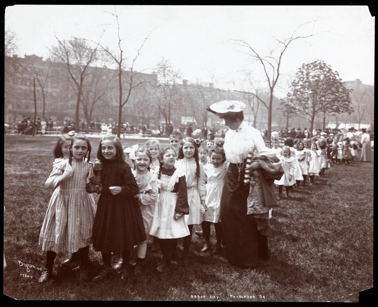Kinderen in een lange rij geleid door een vrouw op Arbor Day in Tompkins Square Park, New York, 1904 door Byron Company
