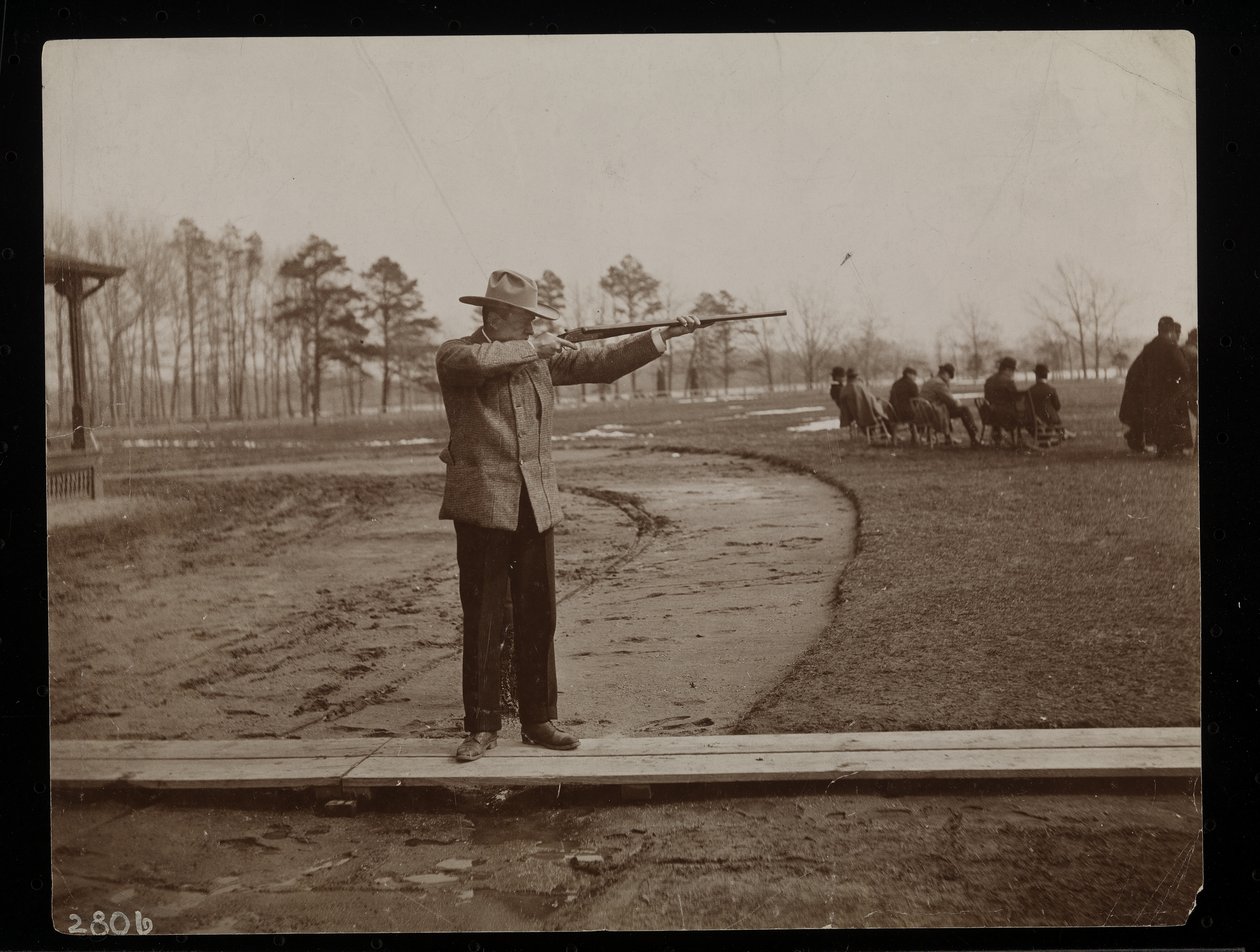 Frank Work richt een geweer op een kleiduifschietbaan, New York, 1896 door Byron Company