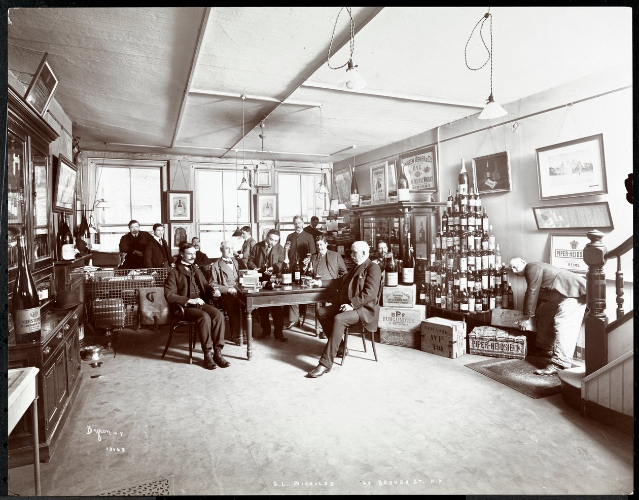 Groep mannen die wijn drinken bij G.L. Nicholas, wijn- en sterke drankhandelaren, 43 Beaver Street, New York door Byron Company