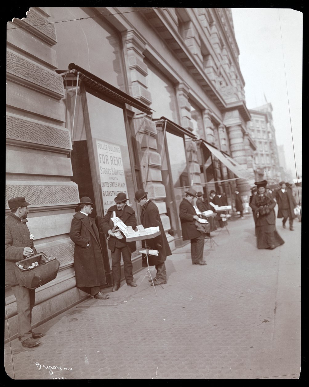 Uitzicht op venters die speelgoed en andere artikelen verkopen voor het Fuller of Flatiron Building aan Broadway, 5th Avenue en 23rd Street, New York, ca. 1895 door Byron Company