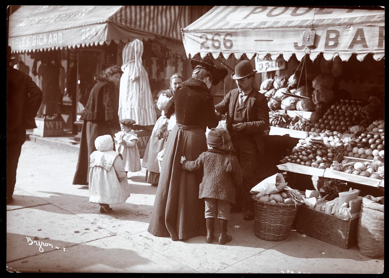 Uitzicht op vrouwen met kinderen die winkelen bij een fruit- en groentekraam op 266 7th Avenue, New York, ca. 1900 door Byron Company