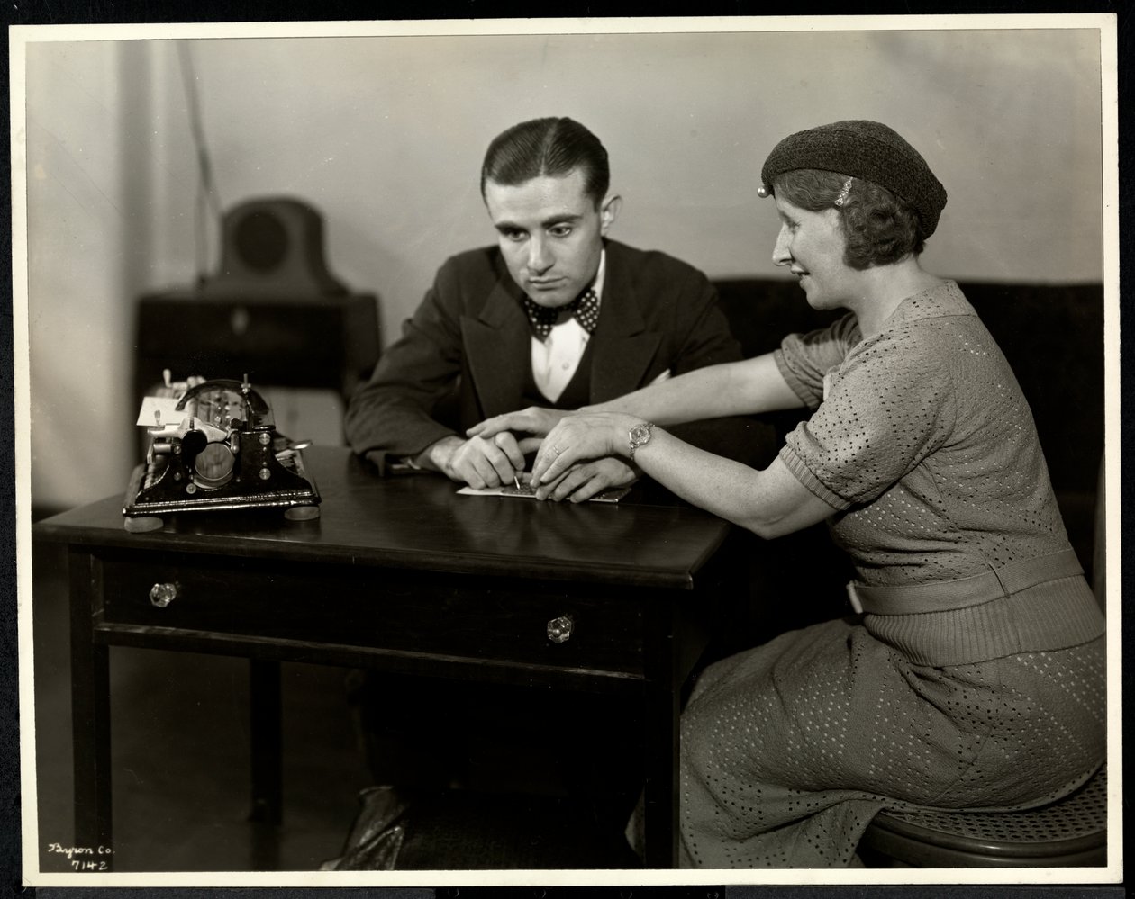 Vrouw leert een blinde man braille lezen bij de New York Association for the Blind, 111 East 59th Street, New York, 1935 door Byron Company