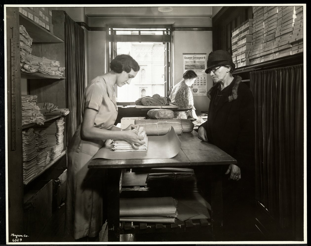 Jonge vrouw die stoffen inpakt voor een thuiswerker om mee te nemen, bij de New York Association for the Blind, 111 East 59th Street, New York, 1931 door Byron Company