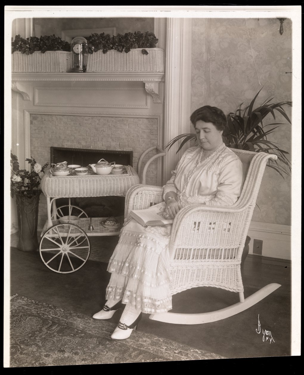 Mevrouw Howard zittend met een boek in een schommelstoel in haar huis op 200, 5th Avenue, New York, 1915-6 door Byron Company