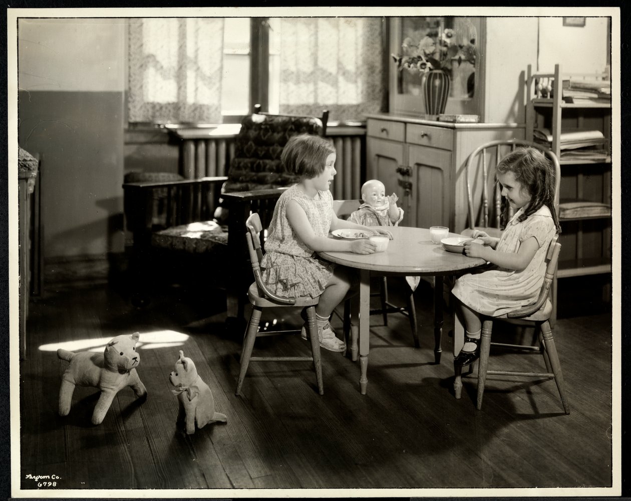 Twee blinde meisjes die eten aan een kleine tafel met een pop bij de New York Association for the Blind, 111 East 59th Street, New York, 1933 (zilveren gelatin afdruk) door Byron Company