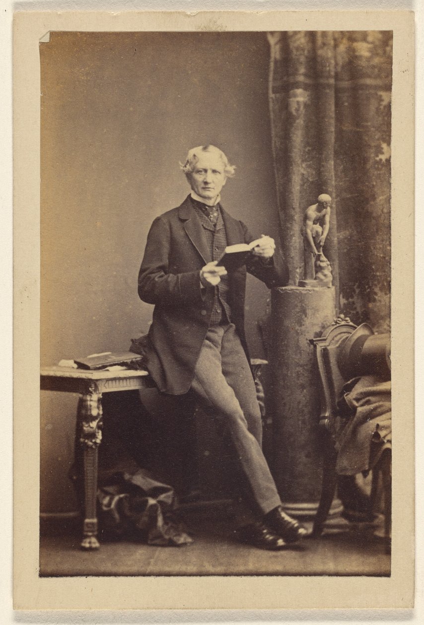 [Ongeïdentificeerde man zit op tafel en houdt een opengeslagen boek vast]. door Camille Silvy