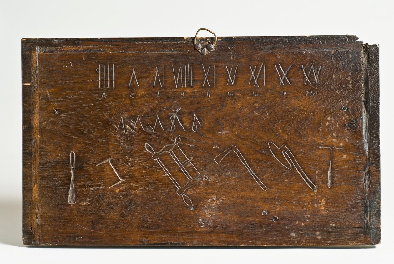 Paneel met Romeinse cijfers (mogelijk ingeschreven met een race mes), onbekende symbolen en omtrekken van een beitel, frame of boogzaag, bijlen en een boor (eik) door E. Tijzer