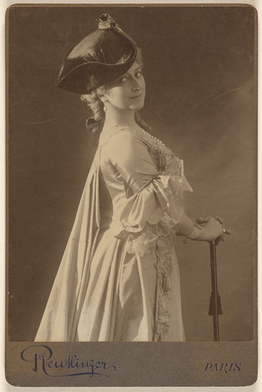 [Ongeïdentificeerde vrouw met donkere hoed, staand, met de handen rustend op een wandelstok]. door Emile Auguste Reutlinger