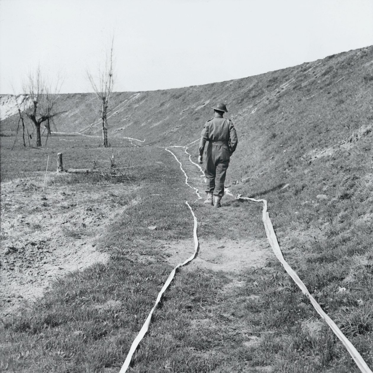 Witte tape markeert veilige paden door een mijnenveld, bij de rivier de Senio, Italië, maart 1945 door English Photographer