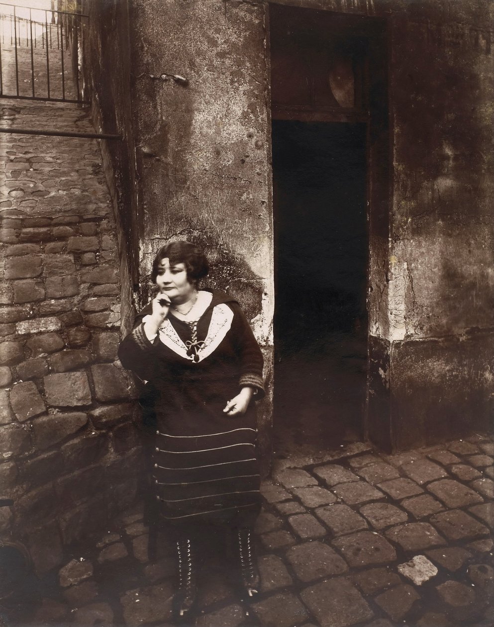 La Villette. Rue Asselin, prostituee wacht voor haar deur door Eugène Atget