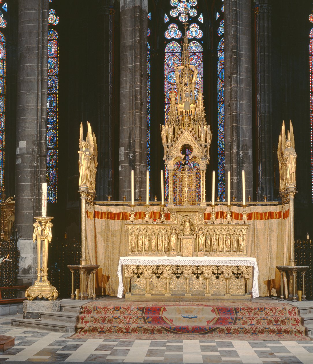 Hoogaltaar in neogotische stijl, omringd door 4 engelen die de instrumenten van de Passie van Christus dragen met een tabernakel bekroond door een rijkelijk versierde torenspits door Eugene Emmanuel Viollet le Duc