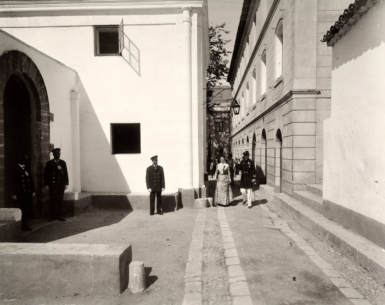 Mannen in uniform begeleiden een elegant geklede vrouw naar de kerk van de boerderij van Lo Zucco, Sicilië, 1900 door Eugenio Interguglielmi
