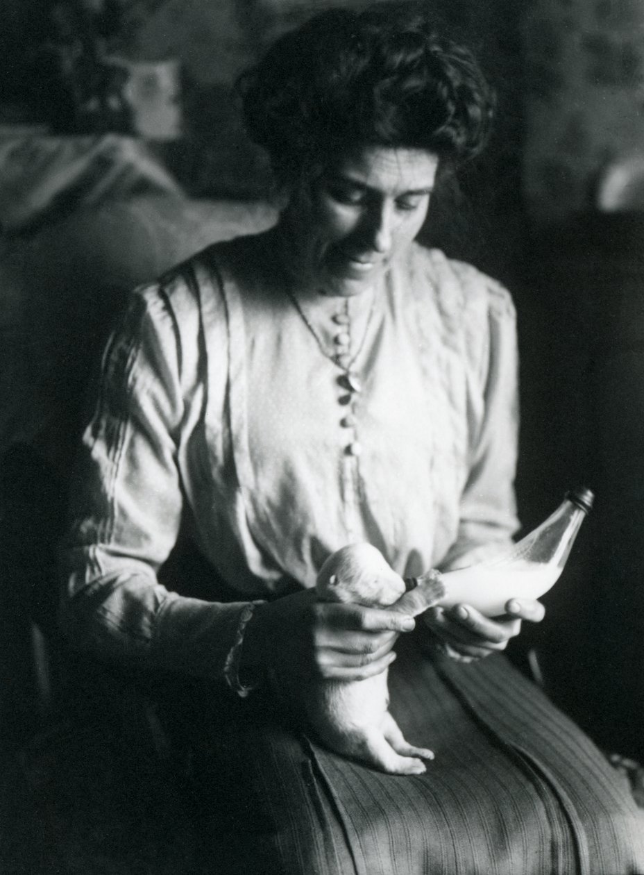 De vrouw van een verzorger voedt een pasgeboren ijsbeerwelp met de fles, London Zoo, c.1914 door Frederick William Bond