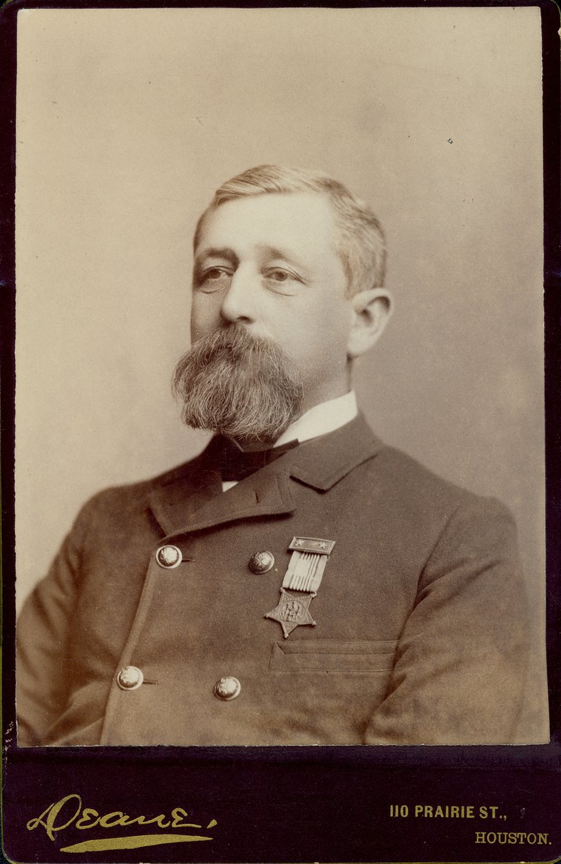 Borstportret van Alfred K. Taylor, naar links gedraaid, en een dubbelrijig jasje dragend met een medaille erop gespeld door Houston Deane