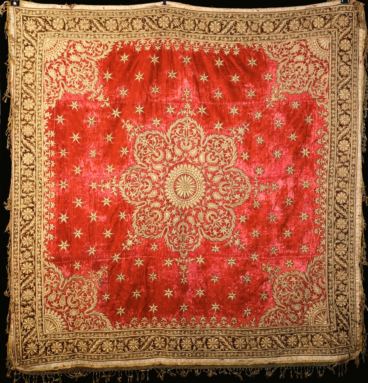 Een scharlaken fluwelen vloerkleed met groene fluwelen rand, dicht geborduurd met vergulde draad door Indian School
