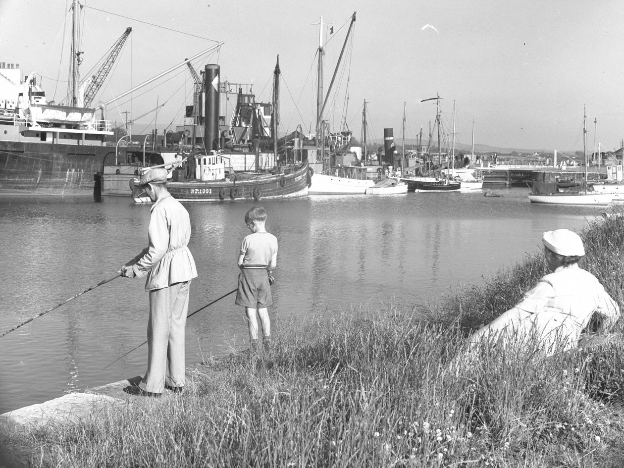 Een man en jongen vissen in Glasson Dock als een dame op zee; zeegezicht;ted achter kijkt toe, verschillende boten aangemeerd door Joseph Hardman