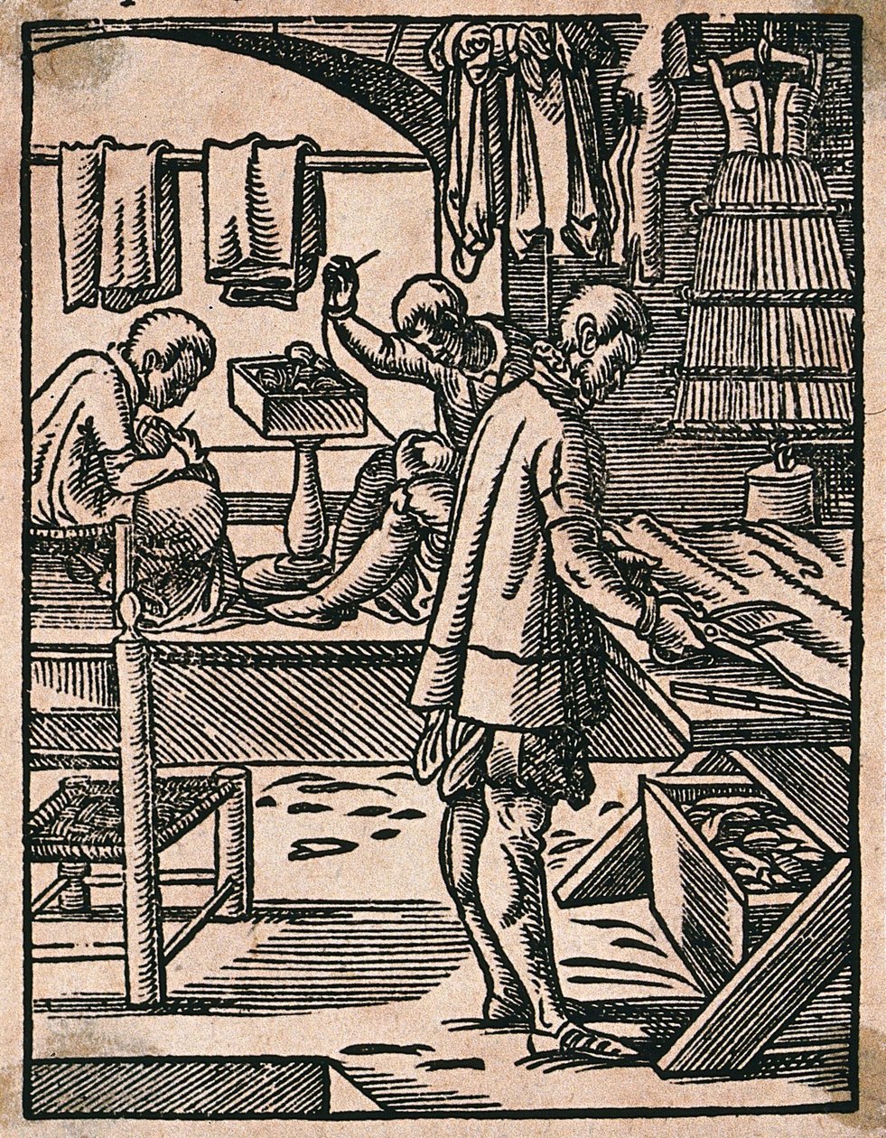 Een kleermaker knipt stof met een schaar terwijl zijn collega