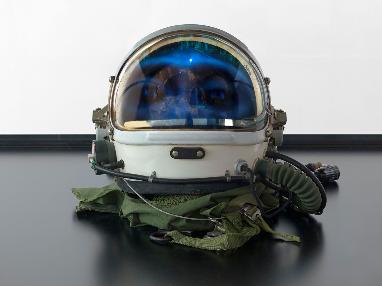 Alpha Omega, 2016 (Glas, LCD-scherm, mediaspeler, replica schedel, ruimtehelm, hout) door Mat Collishaw