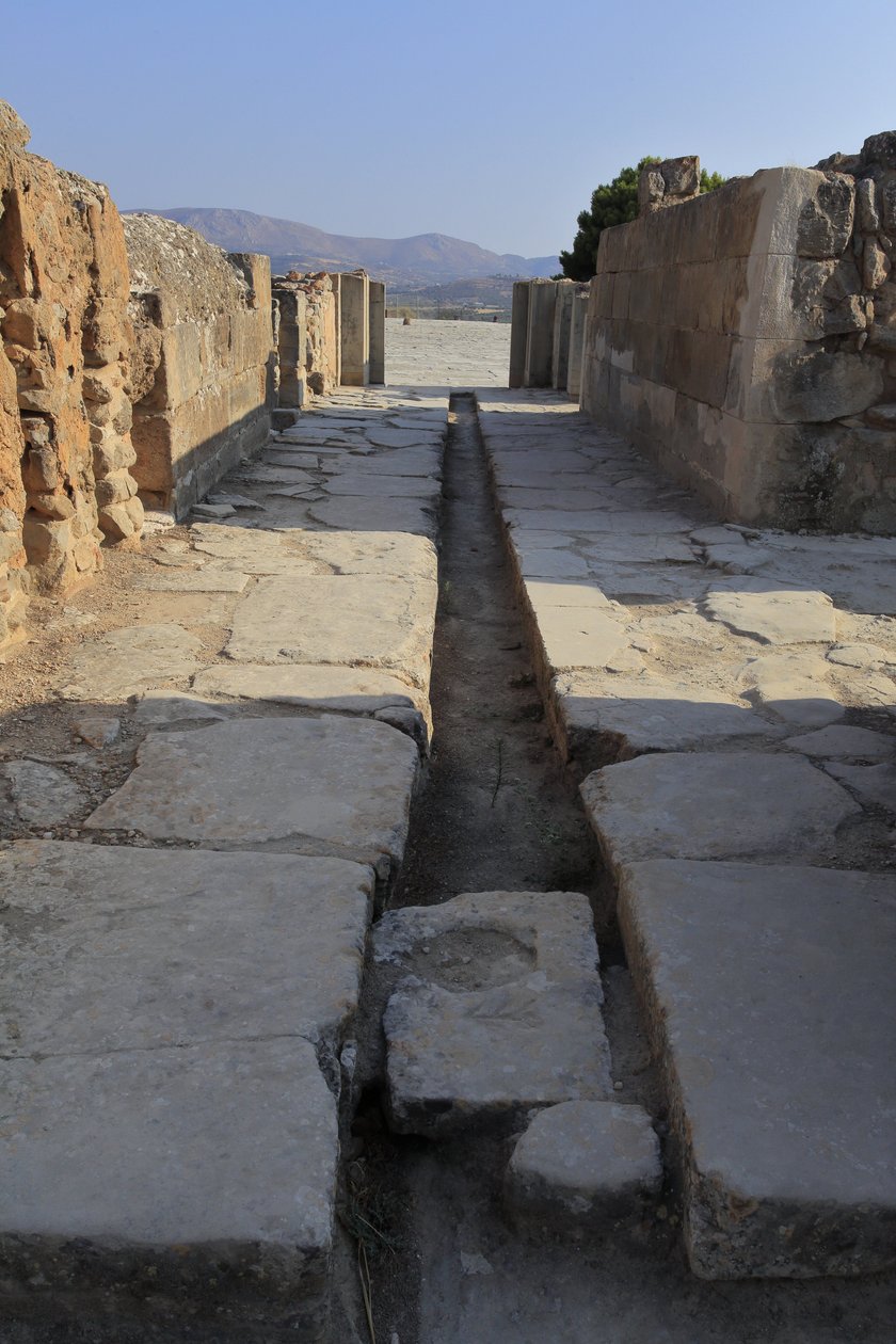 Minoïsch archeologisch terrein van Phaistos. Brede gang met een afvoerkanaal achter de poort van de noordvleugel die uitkomt op de centrale binnenplaats en leidt naar een binnenplaats naast de Koninklijke Appartementen. Phaistos, Kreta door Minoan