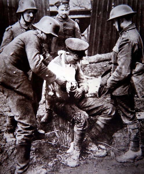 Duitse medische ordonnans verzorgt een gewonde Britse soldaat aan het Westfront tijdens WOI door Photographer German