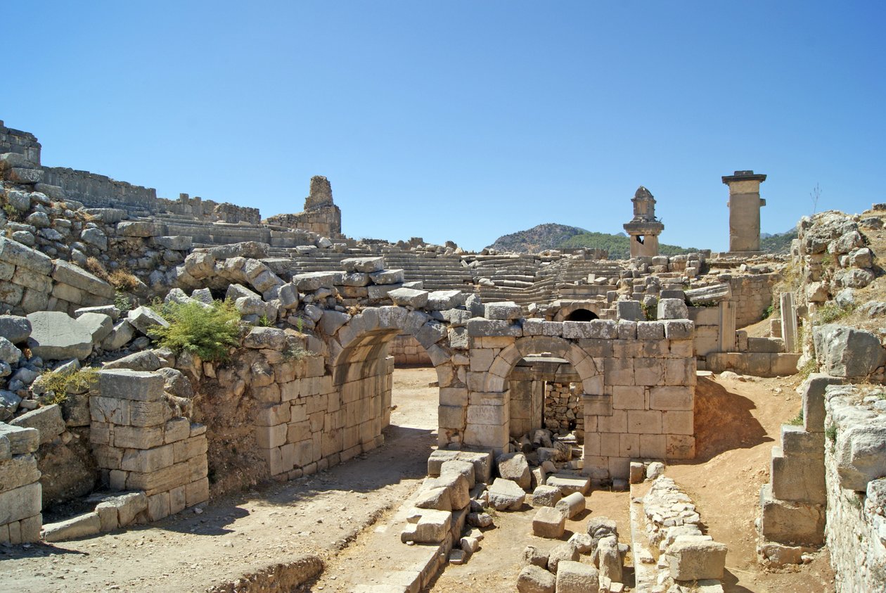 Uitzicht door de gewelfde ingang van het Xanthos-theater naar de orkestbak, met zuil en Harpy-tombe, Xanthos, Turkije door Roman