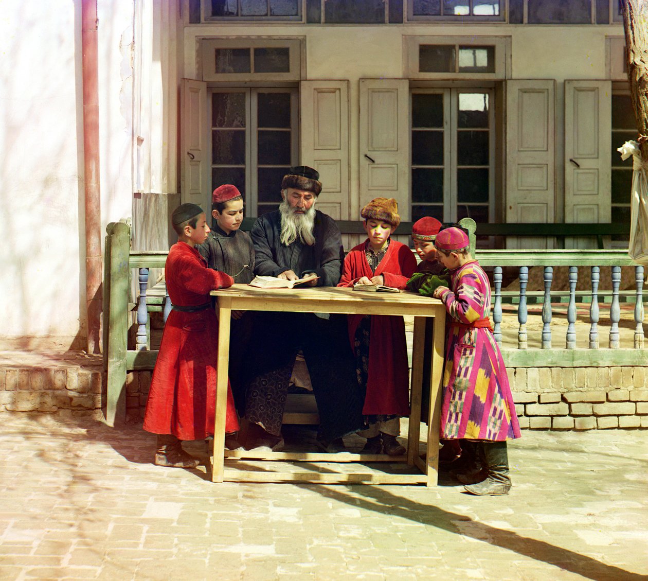 Een groep Joodse kinderen met een leraar aan een tafel voor een huis, Samarkand, Russisch Rijk, tussen 1905 en 1915 door Sergey Prokudin Gorsky