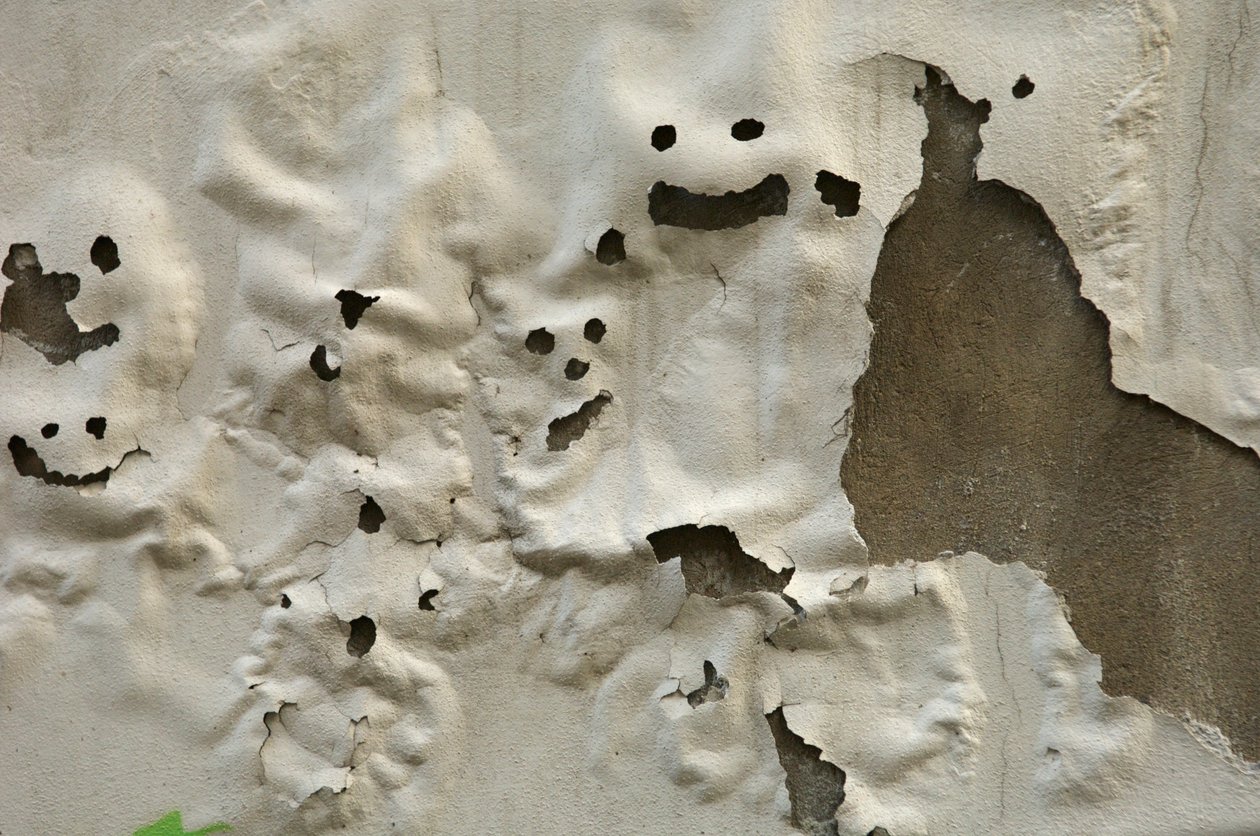 Italië, Toscane, Florence, Lachende spookgezichten op verweerde geschilderde muur, 2022 (foto) door Sisse Brimberg