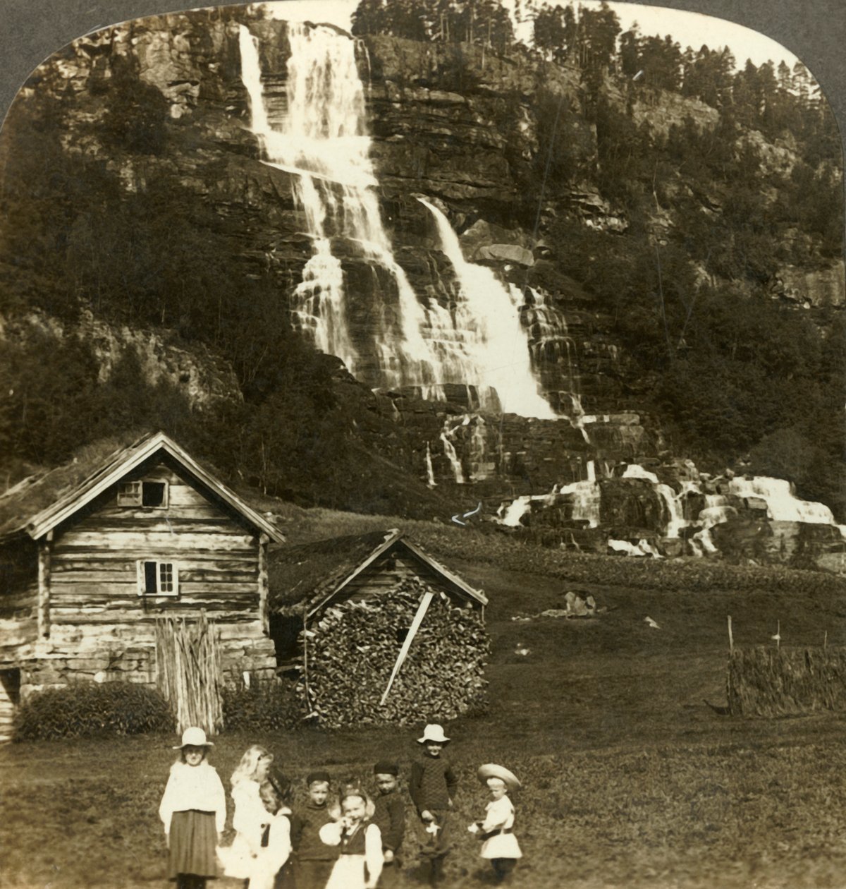 Kinderen die spelen in een boerenveld met terrasvormige Tvinde-waterval, Vossevangen, Noorwegen, ca. 1905 door Unbekannt