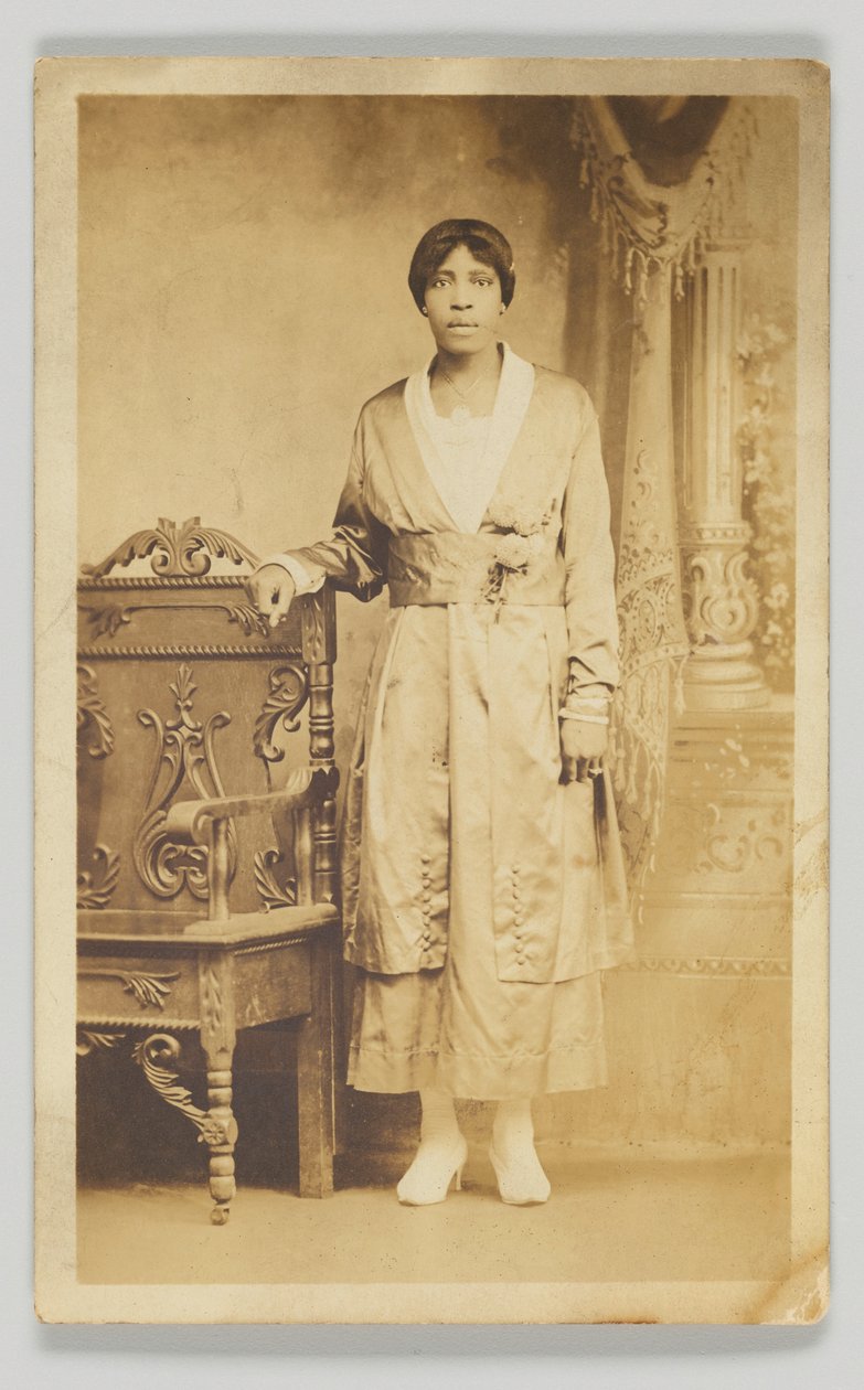 Fotografische ansichtkaart van een vrouw naast een houten stoel, 1904-1918 door Unbekannt