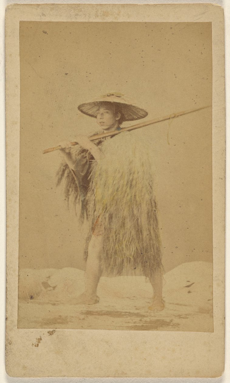 [Japanse man draagt strooien regencape en hoed, en draagt een lange stok]. door Unknown artist