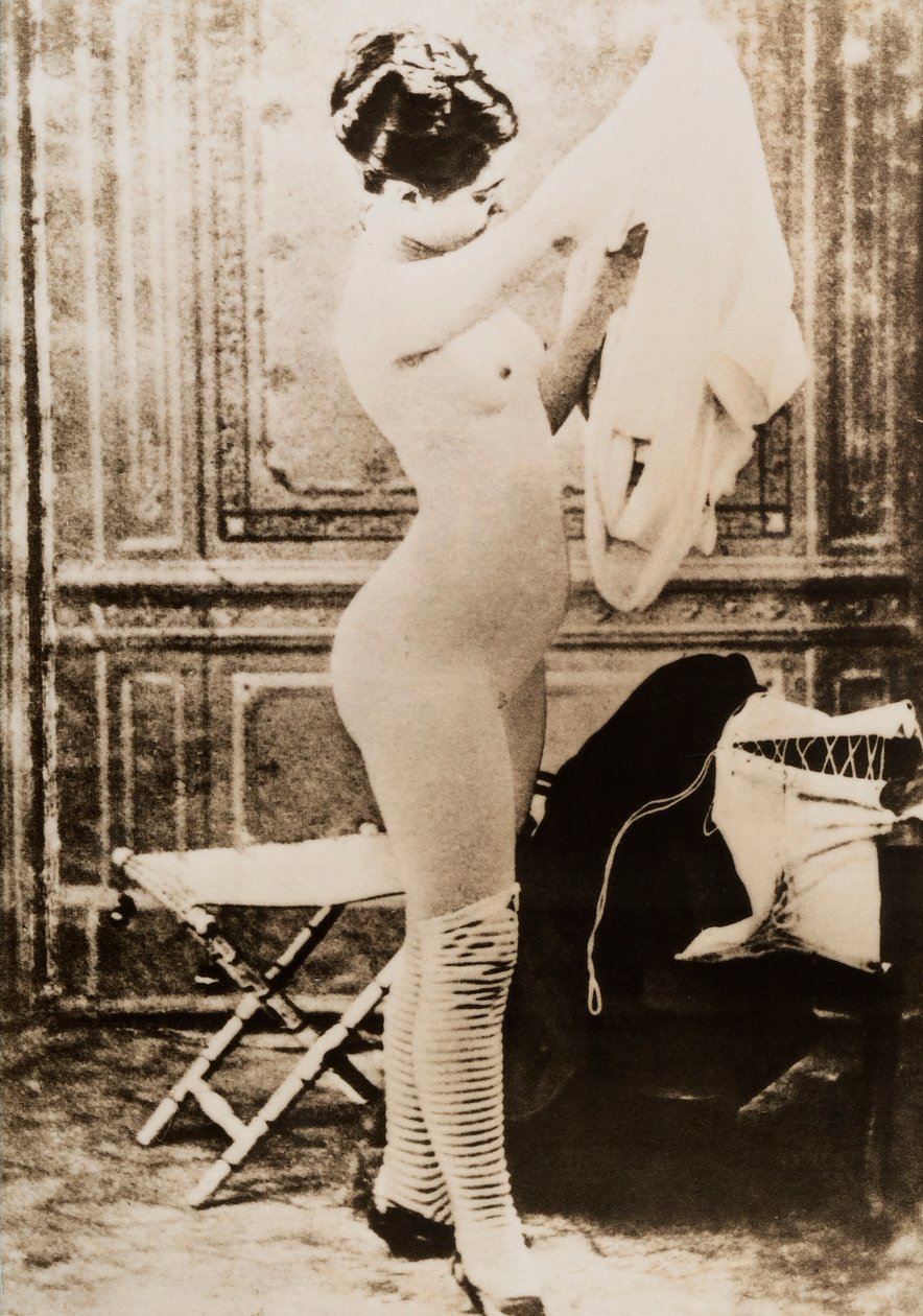 Volledig naakt portret van een jonge vrouw die zich aankleedt. door Unknown photographer