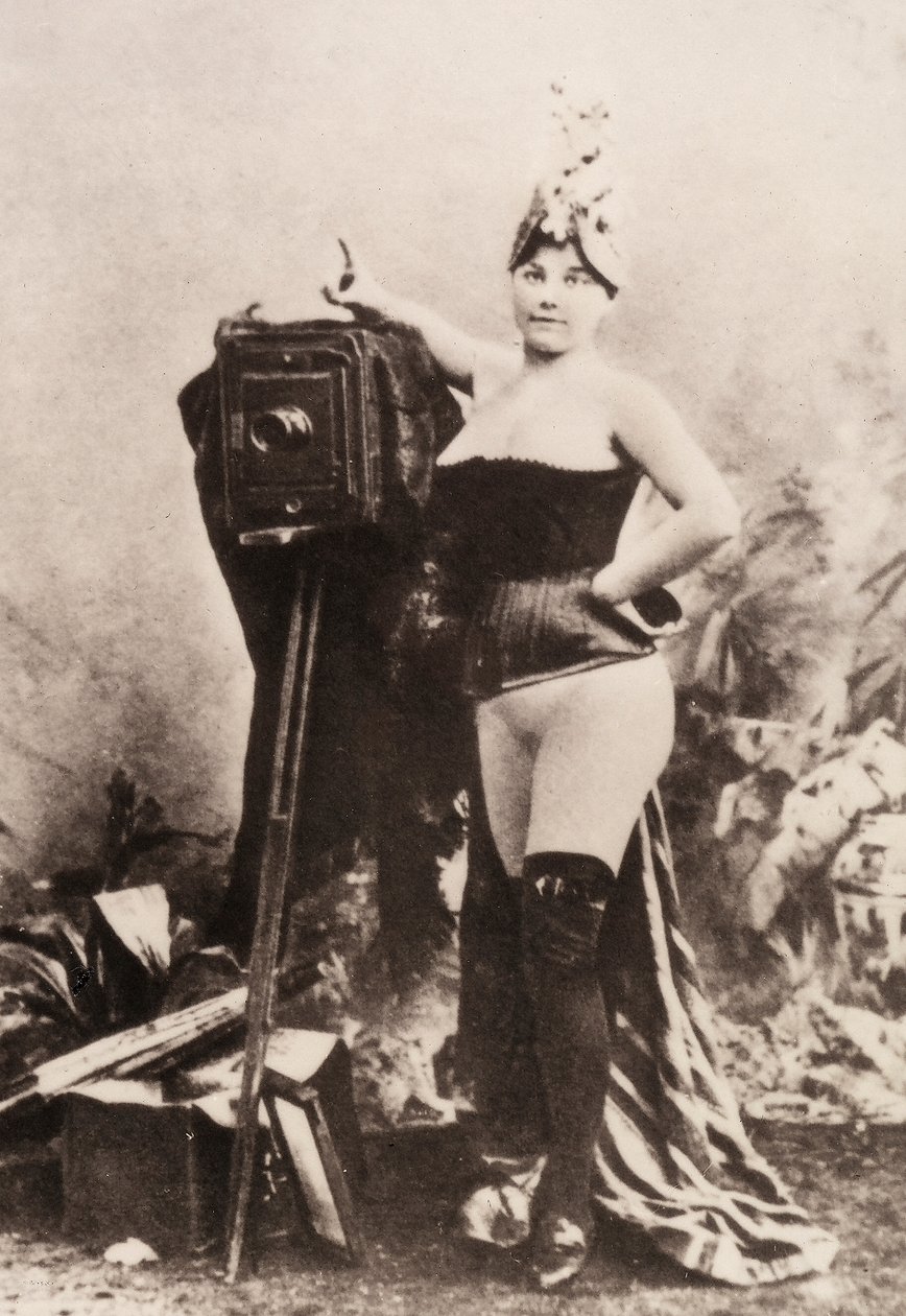 Portret van een gedeeltelijk naakte vrouw leunend op een antieke camera. door Unknown photographer