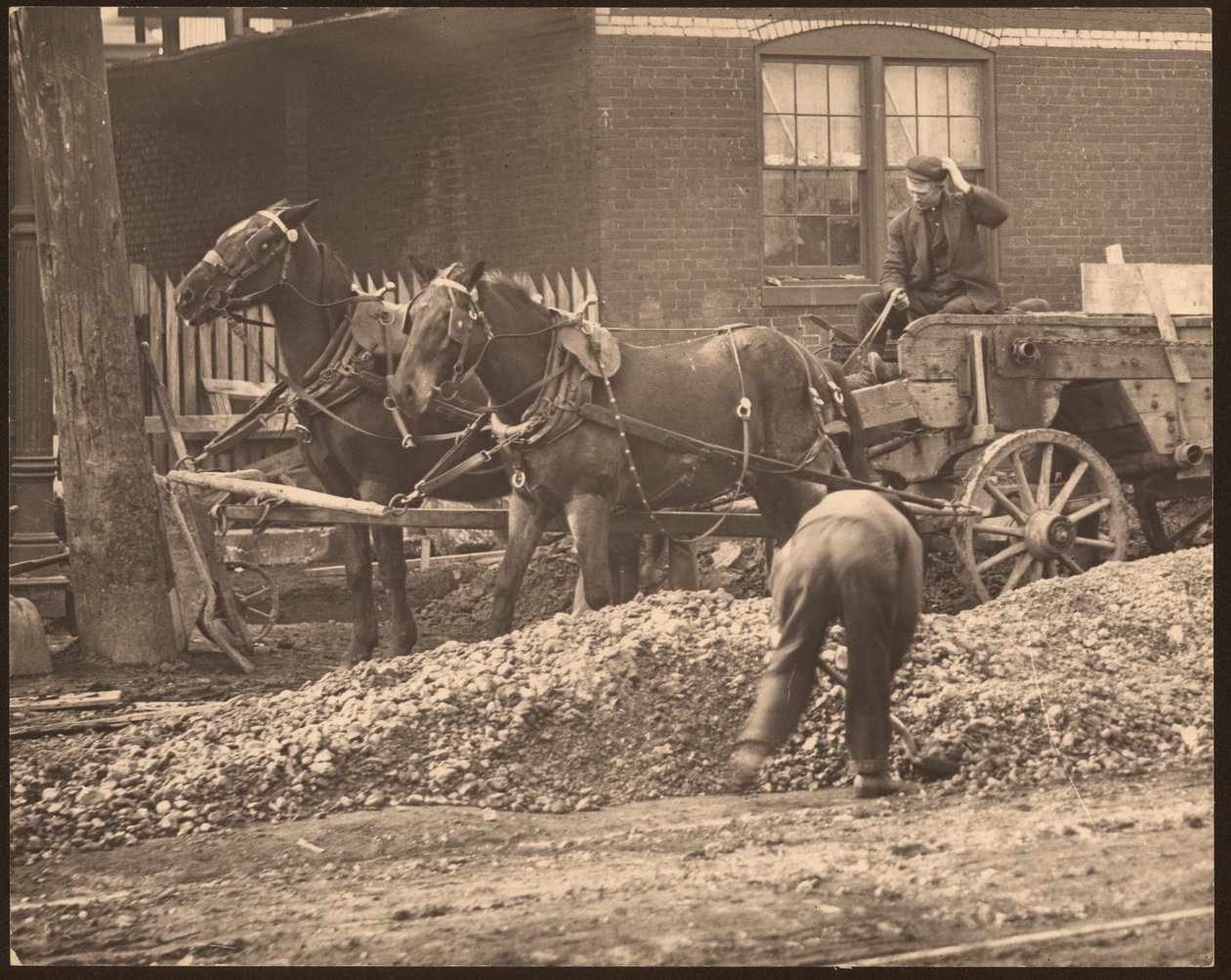 Horizontale zwart-wit foto van een door paarden getrokken wagen op een bouwplaats. Een man schept vuil en stenen terwijl een ander de wagen bestuurt door William G. Swekosky