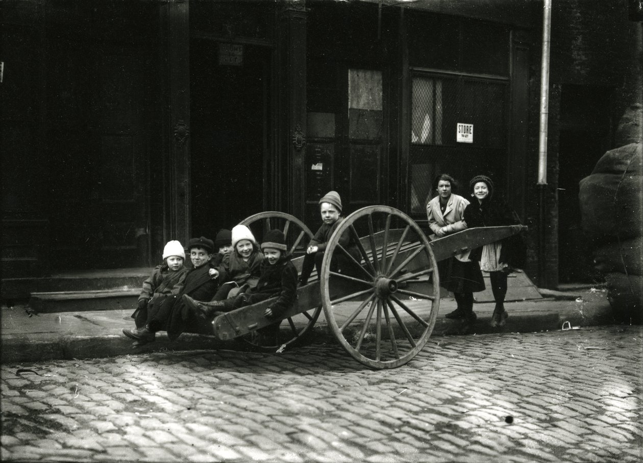 Groep kinderen in kar, met meisje en vrouw staand erachter, ca. 1910-21 door William Davis Hassler