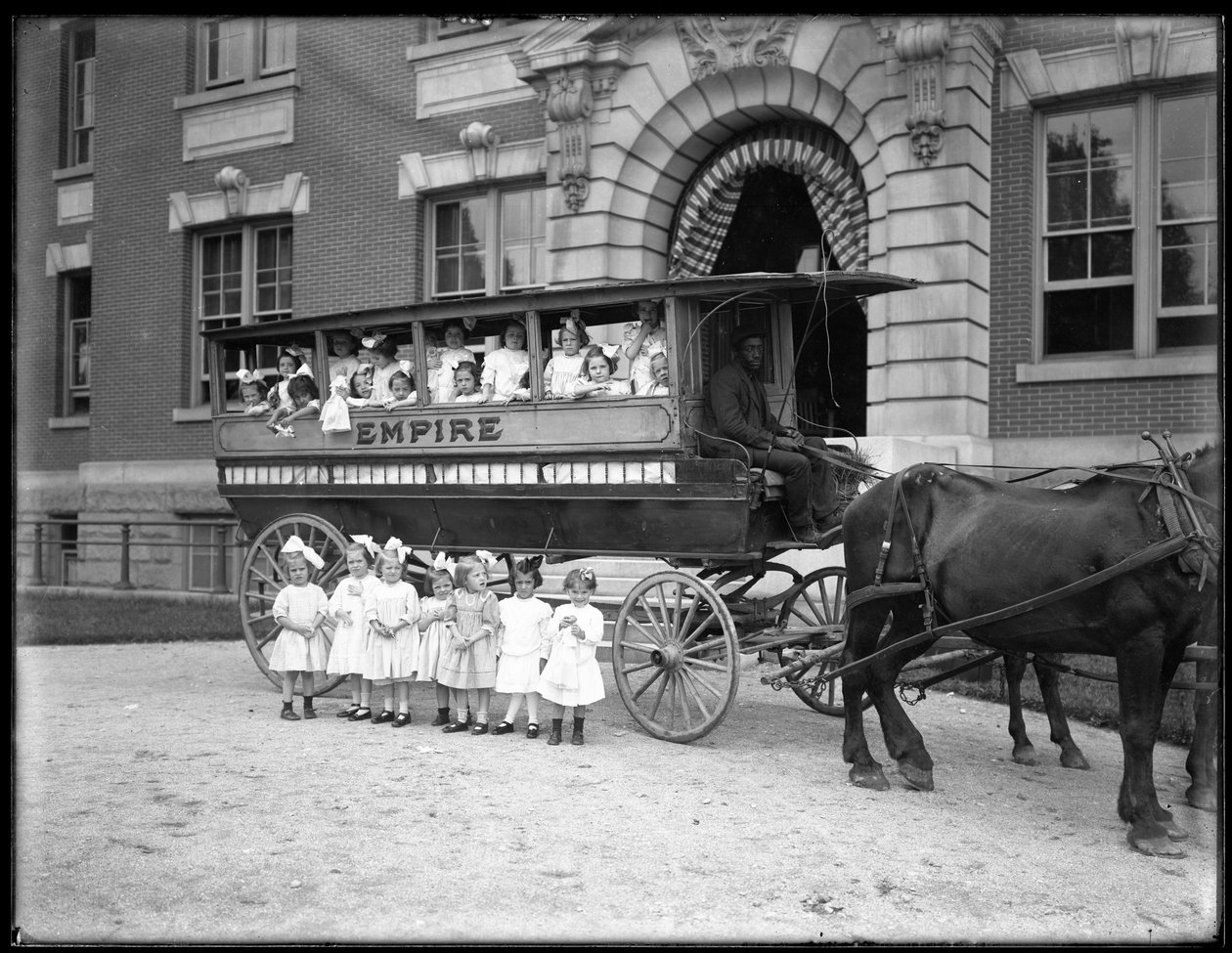 Kleine meisjes poseren in en voor een door paarden getrokken wagen, voor een onbekend gebouw, waarschijnlijk het Rooms-Katholieke Weeshuis, Kingsbridge, Bronx, c.1910 door William Davis Hassler