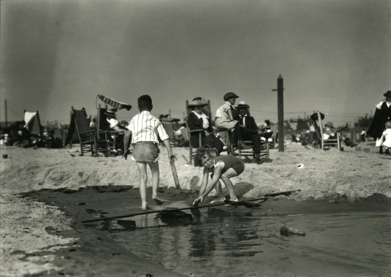 Twee kinderen spelen met houtresten in ondiep water, Coney Island, ca. 1910-21 door William Davis Hassler