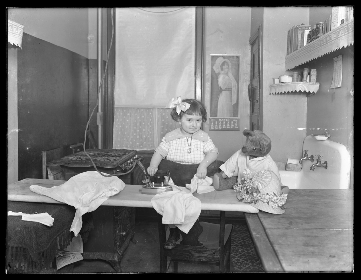 Onbekend klein meisje demonstreert het gebruik van een elektrische strijkijzer, c.1913-14 door William Davis Hassler