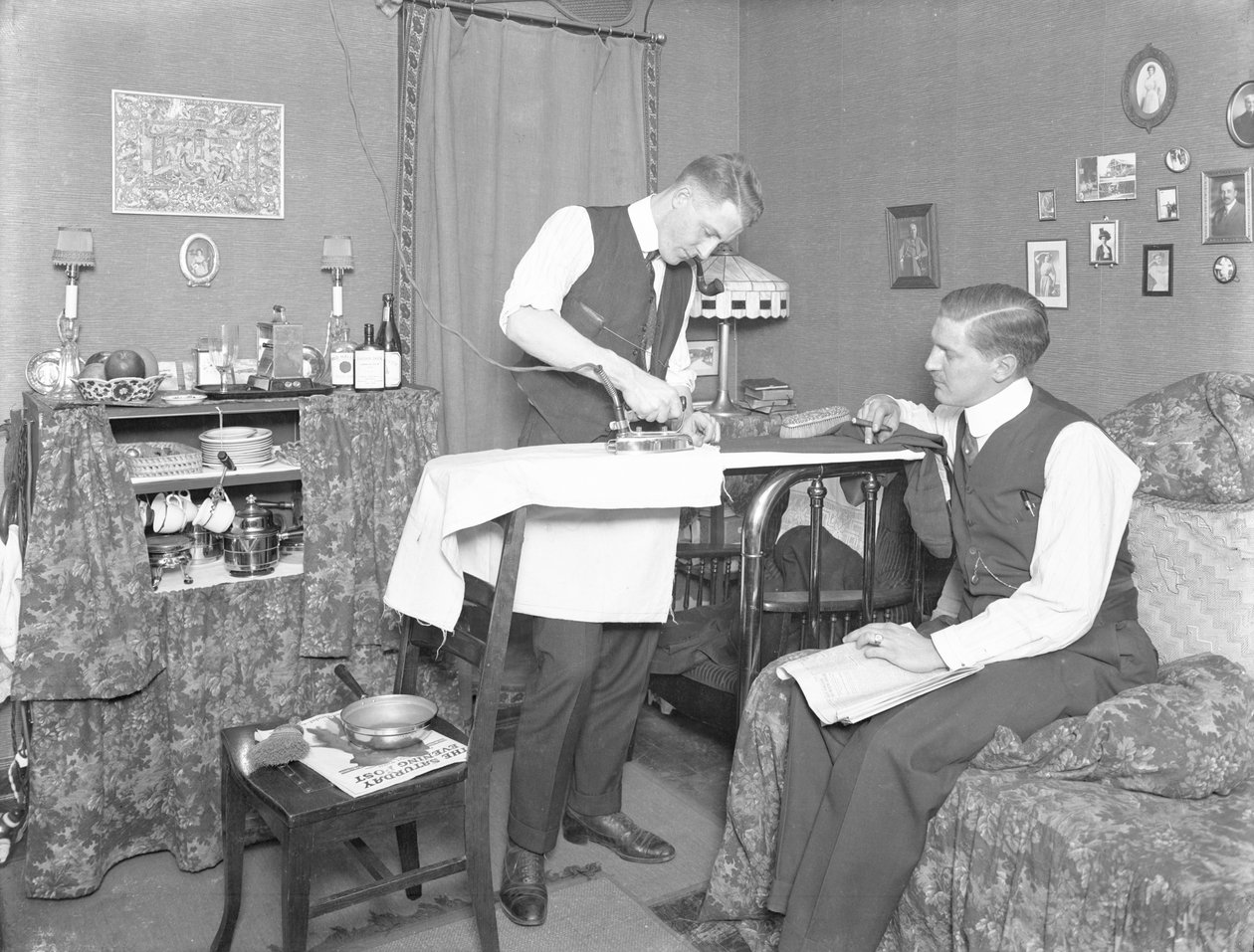Onbekende man demonstreert het gebruik van een elektrisch strijkijzer, bekeken door een andere man, c.1913-14 door William Davis Hassler