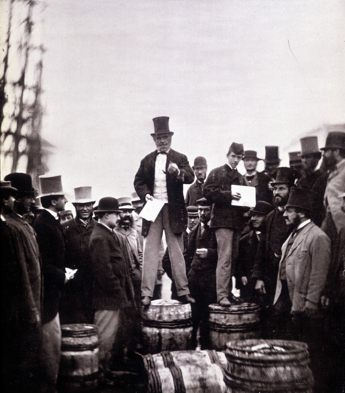 Scène van politieke redevoering op straat: de man staat op een vat en spreekt tot een uitsluitend mannelijk publiek. Foto door William Notman (1826-1891), Musee McCord Museum, Montreal. Eind 19e eeuw door William Notman
